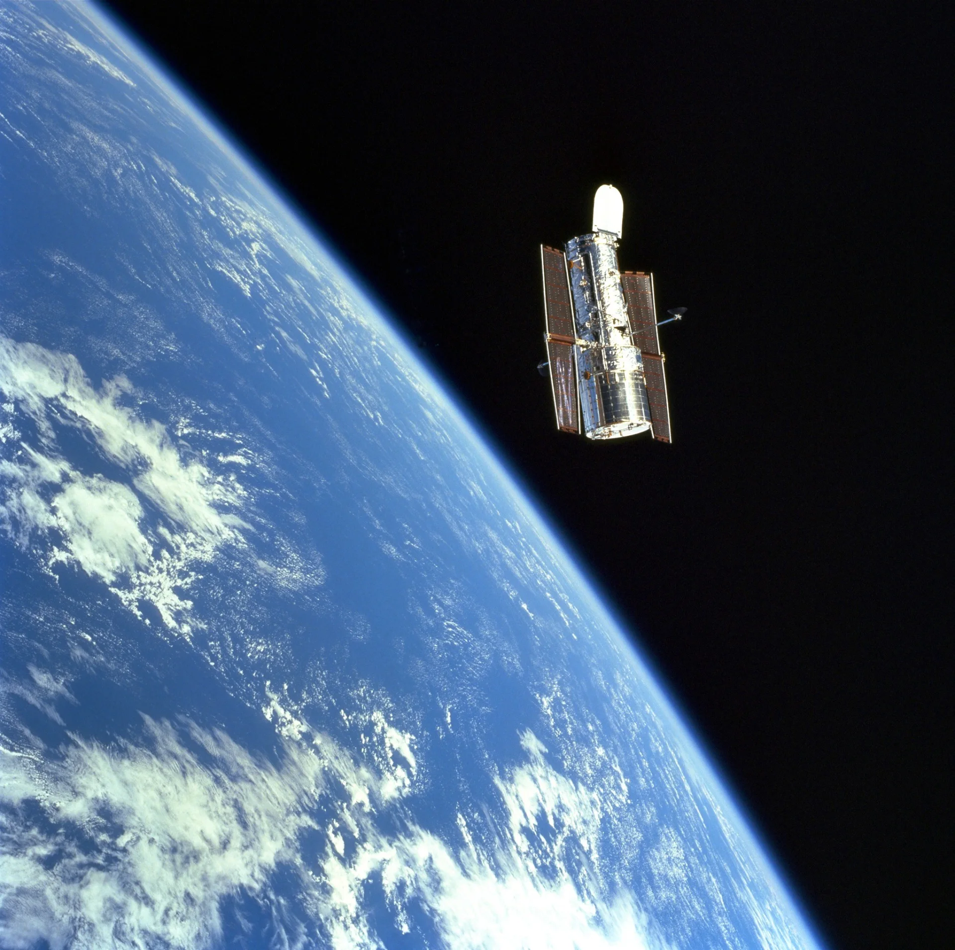 Hubble Space Telescope orbiting above the curved Earth