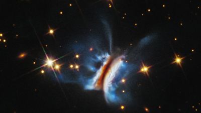 Imagen del Telescopio Espacial Hubble del Chivito de Drácula (IRAS 23077+6707), el mayor disco protoplanetario caótico jamás observado, con filamentos brillantes de polvo que se extienden por encima y por debajo del disco oscuro visto de canto.