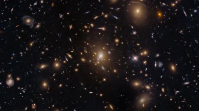 Hubble Space Telescope image of galaxy cluster MACS0329-0211, showing a figure-eight gravitational lens at the center and faint lensed arcs of distant galaxies in the upper-right quadrant.