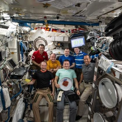 The seven-member Expedition 74 crew gathers for a portrait inside the International Space Station