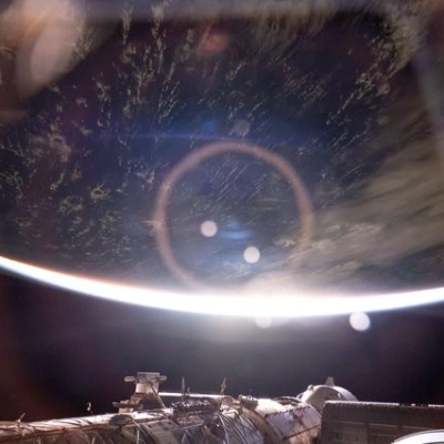 The light from an orbital sunrise refracts through a window inside the International Space Station