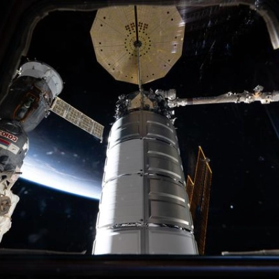 Two spacecraft attached to the International Space Station are seen through a window in the cupola